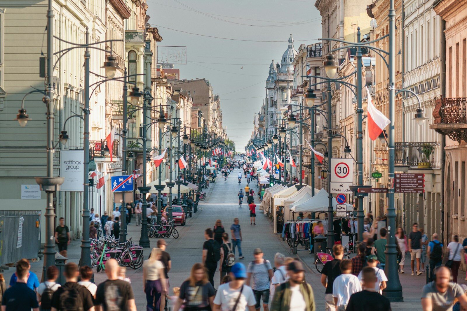 People walk down a busy street lined with buildings.