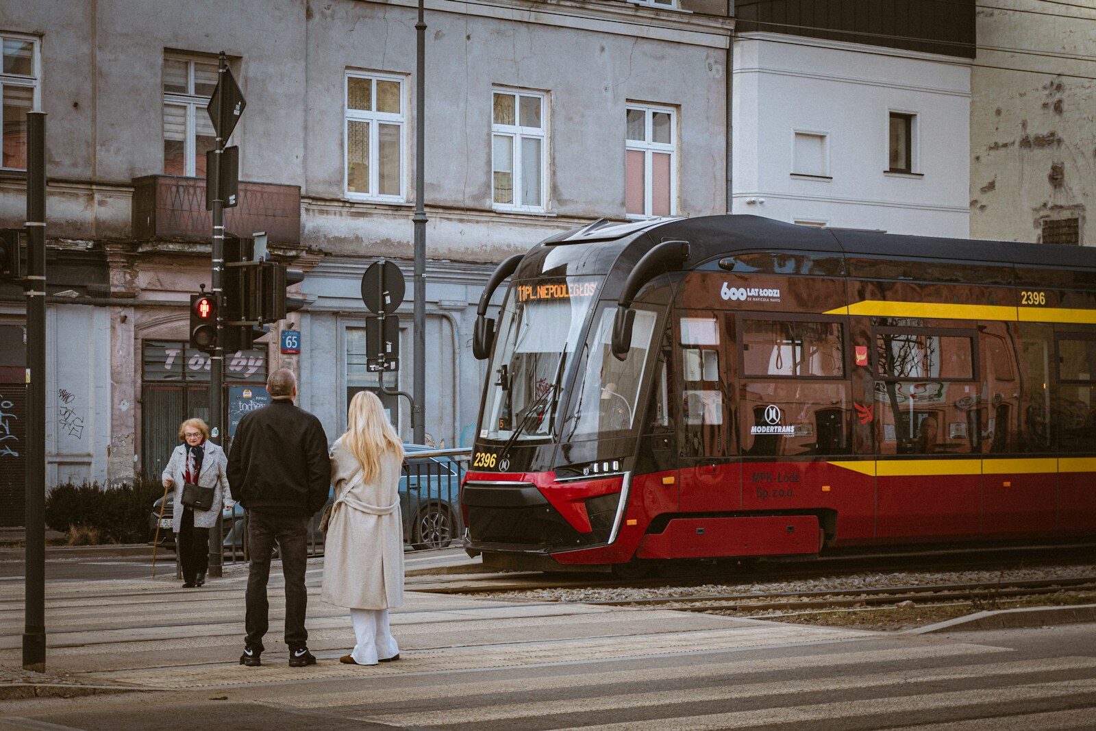 People wait to cross street as tram approaches